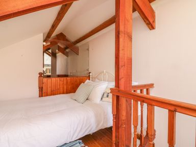 A bedroom with a bed and wooden beams and railing at The Wagon House in Tresmeer near Launceston