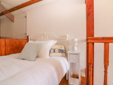 A bedroom with a white metal bed frame pillows and a bedside table with a lamp at The Wagon House Tresmeer near Launceston