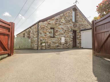 A stone house with a driveway and open wooden gates at The Wagon House in Tresmeer near Launceston