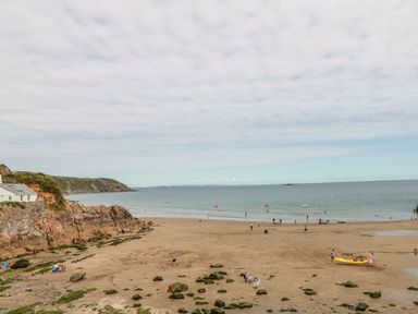A beach with people, boats, and rocks at Dovecote in Gorran Haven