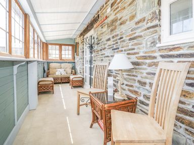 A conservatory with seating and tables at Dovecote in Gorran Haven