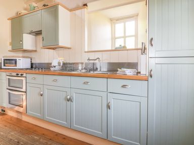 A kitchen with cabinets and sink at Dovecote in Gorran Haven