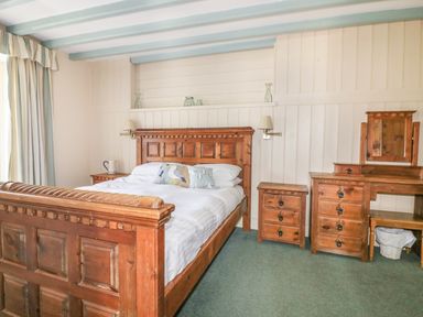 A bedroom with a wooden bed and nightstand at Dovecote in Gorran Haven