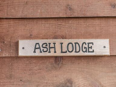 A wooden sign with ASH LODGE mounted on a wooden wall at The Ash Lodge near Lyme Regis