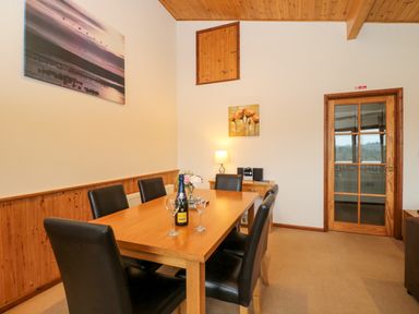 A dining room with a wooden table and six black chairs at The Ash Lodge near Lyme Regis
