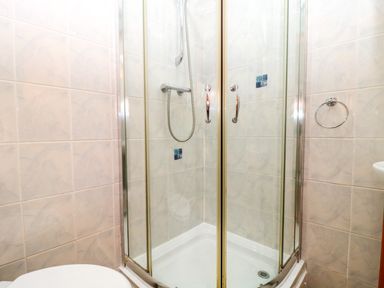 A corner shower enclosure with glass doors and tiled walls in a bathroom at The Ash Lodge near Lyme Regis