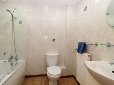 A bathroom with a bathtub shower combination toilet sink towel on a rack and tiled walls at The Ash Lodge near Lyme Regis