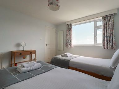 A bedroom with two beds and a table at Treverrion in Gorran Haven