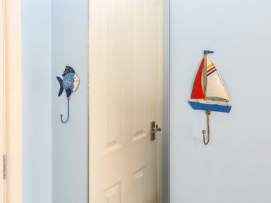 A corner with a white door and light blue walls with a fish hook and a sailboat hook at En-Casa in Mundesley