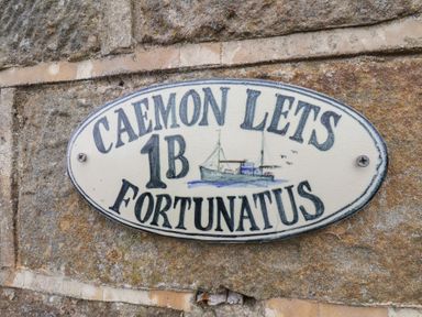 A sign stating CAEMON LETS 1B FORTUNATUS on a stone wall in Whitby