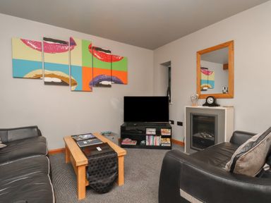 A living room with a couch, coffee table, and television at Fortunatus in Whitby