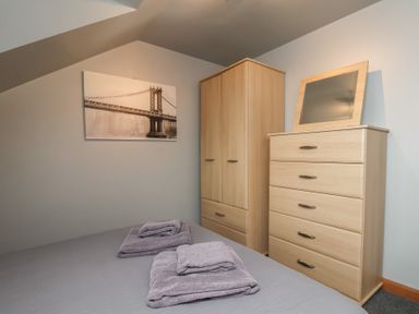 A bedroom with a bed, towels, wardrobe, and a chest of drawers at Fortunatus in Whitby