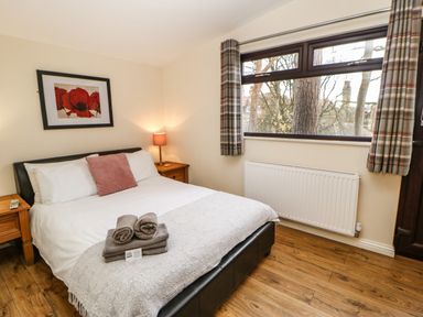 A bedroom with a double bed towels on bed two bedside tables with lamps and a window with plaid curtains at Snowdrop in Saltburn-by-the-Sea