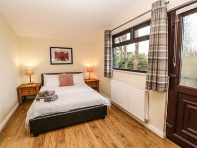 A bedroom with a double bed two bedside tables lamps a window with curtains and a wooden door at Snowdrop in Saltburn-by-the-Sea