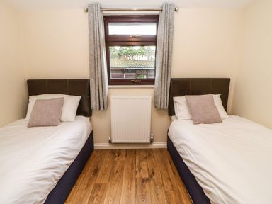 A bedroom with two single beds with pillows and a window with curtains at Snowdrop in Saltburn-by-the-Sea