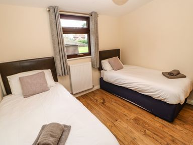 A bedroom with two single beds with white bedding and brown pillows and towels on them at Snowdrop in Saltburn-by-the-Sea
