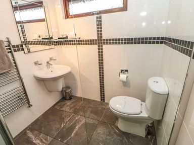 A bathroom with a toilet sink mirror towel rack and tiled floor at Snowdrop in Saltburn-by-the-Sea
