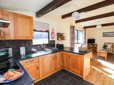 A kitchen with wooden cabinets and a sink at Snowdrop in Saltburn-by-the-Sea
