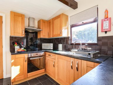 A kitchen with wooden cabinets and stainless steel appliances at Snowdrop in Saltburn-by-the-Sea