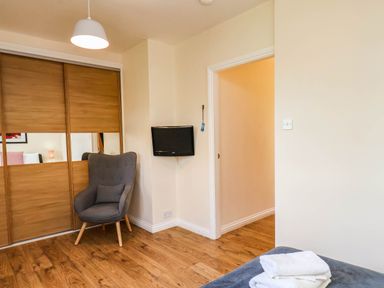 A bedroom with a chair and television at Snowdrop in Saltburn-by-the-Sea