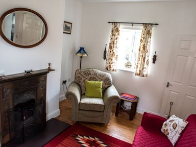 A sitting room with an armchair, sofa, fireplace, wall mirror, and window at Anvil Lodge in Goulceby near Louth
