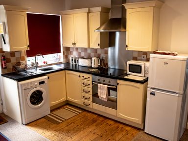 A kitchen with washing machine sink toaster kettle oven and microwave at Anvil Lodge in Goulceby near Louth