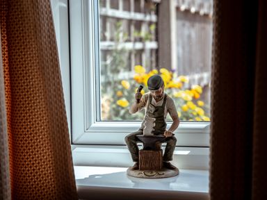 A figurine of a blacksmith working on an anvil on a windowsill with yellow flowers outside at Anvil Lodge in Goulceby near Louth