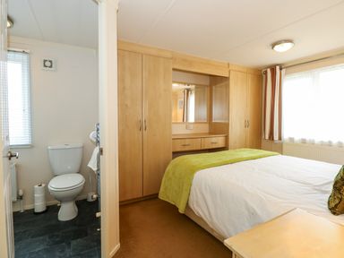A bedroom with a bed and built in wardrobes next to an en suite bathroom at Jolie in Hunstanton