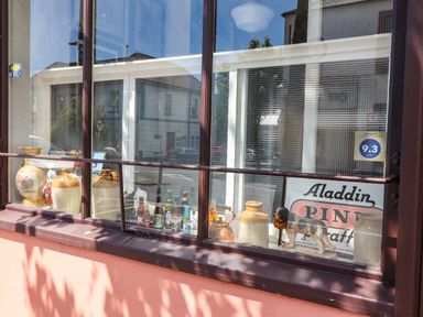 A window display with ceramic jugs bottles a dog figurine and a sign at The Merchant's Store in Kilrush Country Clare