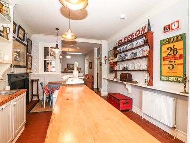 A kitchen with a long wooden table blue chairs shelves with plates and vintage signs at The Merchant's Store in Kilrush Country Clare