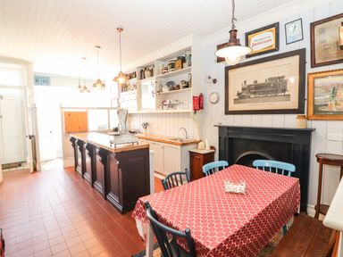 A kitchen with a wooden island and a table with red tablecloth at The Merchant's Store in Kilrush Country Clare