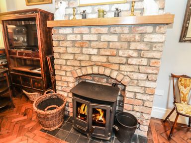 A brick fireplace with a wood burning stove and burning fire at The Merchant's Store in Kilrush Country Clare