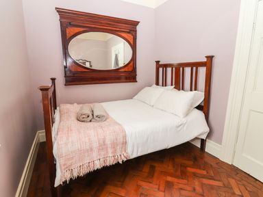 A bedroom with a wooden bed with white bedding and towels on a blanket under a large wood framed mirror on the wall at The Merchant's Store in Kilrush Country Clare