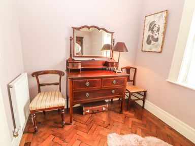 A corner of a room with wooden dresser mirror two chairs a floor lamp and a framed picture at The Merchant's Store in Kilrush Country Clare