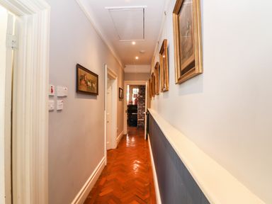 A hallway with framed pictures on the walls and a wooden floor at The Merchant's Store in Kilrush Country Clare