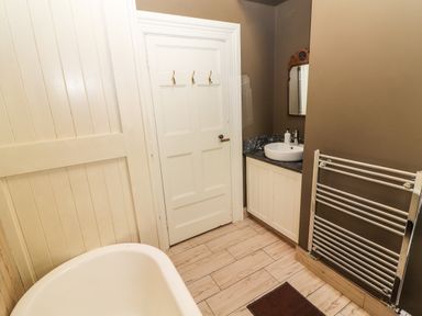A bathroom with a clawfoot tub door sink with mirror and towel rack at The Merchant's Store in Kilrush Country Clare