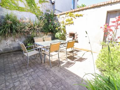 An outdoor patio with a glass table and six chairs surrounded by plants at The Merchant's Store in Kilrush Country Clare