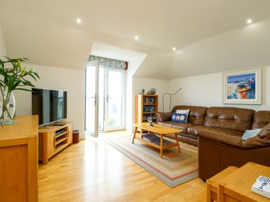 A living room with a sofa and television at Maelog, 14 Tides Reach Rhosneigr