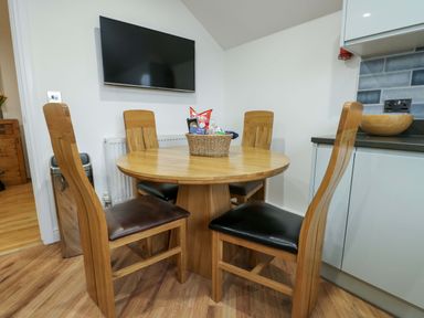 A dining room with a round wooden table and chairs at Maelog, 14 Tides Reach, Rhosneigr