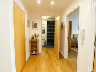 A hallway with wooden flooring and doors at Maelog, 14 Tides Reach Rhosneigr
