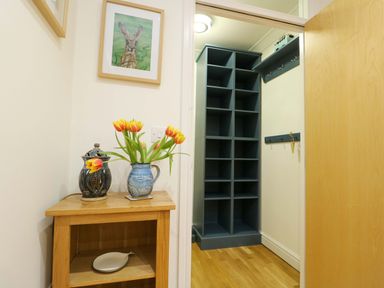 A hallway with a flower vase and framed artwork at Maelog, 14 Tides Reach Rhosneigr