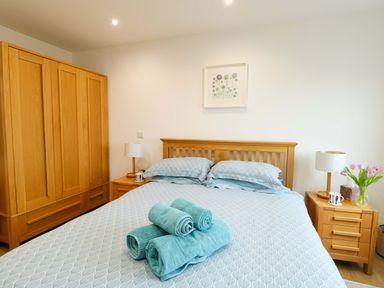 A bedroom with a bed, wardrobe, and nightstands at Maelog, 14 Tides Reach Rhosneigr