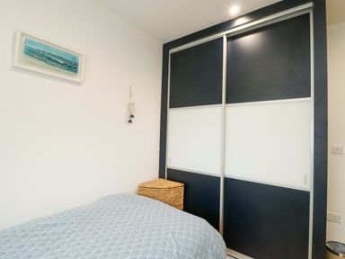 A bedroom with a bed and wardrobe at Maelog, 14 Tides Reach, Rhosneigr