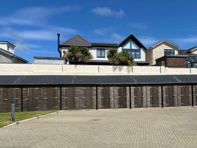 A row of garages and houses with a palm tree at Maelog, 14 Tides Reach, Rhosneigr