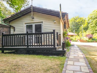 A small house with a black wooden porch and metal chairs on a tiled pathway at Badger View in Culverstone Green near Chatham