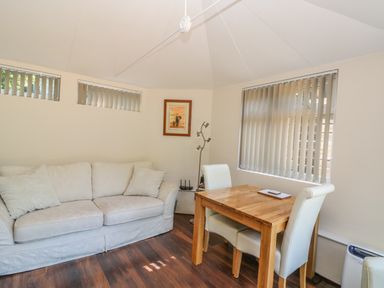 A room with a white sofa a wooden table with two white chairs and vertical blinds on windows at Badger View in Culverstone Green near Chatham