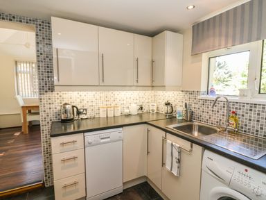A kitchen with white cabinets black countertops dishwasher washing machine and a sink at Badger View in Culverstone Green near Chatham