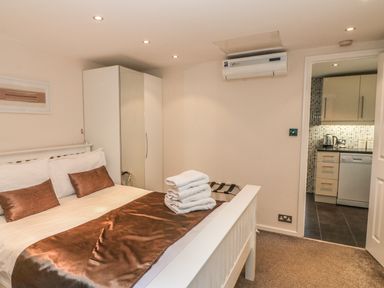 A bedroom with a double bed and wardrobe next to a kitchen at Badger View in Culverstone Green near Chatham