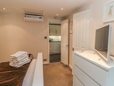 A bedroom with a bed and folded towels a dresser with a TV and an open door leading to a kitchen at Badger View in Culverstone Green near Chatham