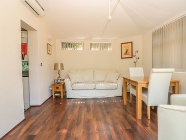 A living room with a white sofa wooden side table dining table and chairs at Badger View in Culverstone Green near Chatham
